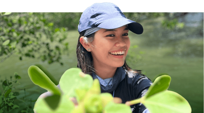 Ney smiling among mangrove leaves.